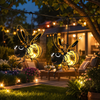 Solar iron bee garden lights glowing in a garden at night